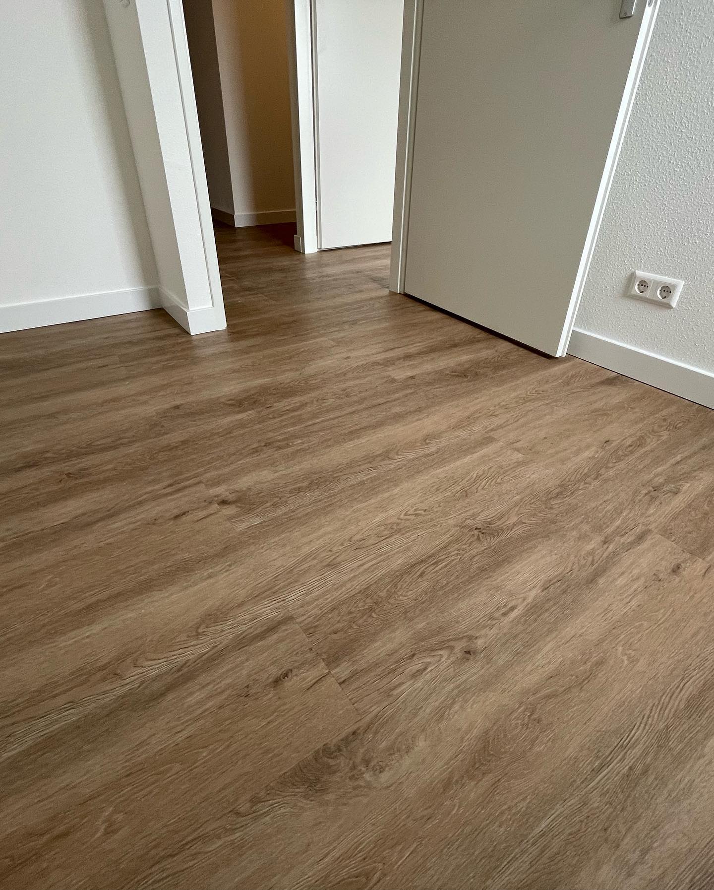 Nieuw gelegde pvc-vloer in houtlook met witte plinten en deuren