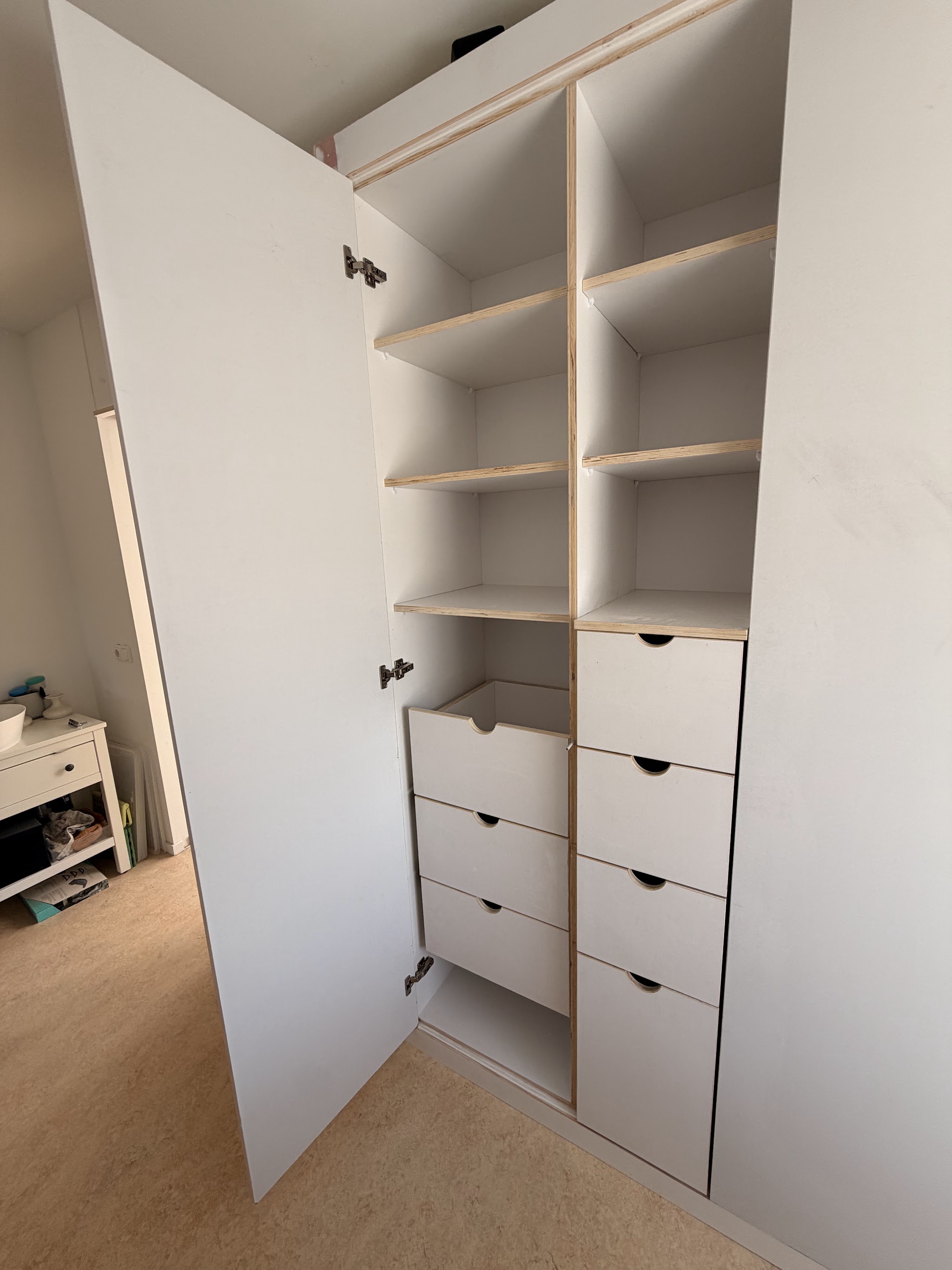 Witte maatwerk inbouwkast met open planken en laden, deur open