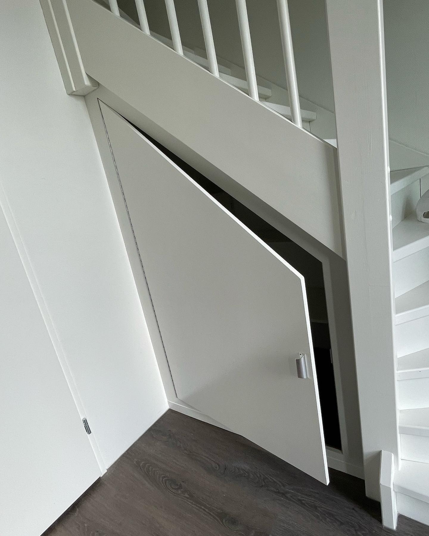 Trapkast met schuine deur onder een witte trap