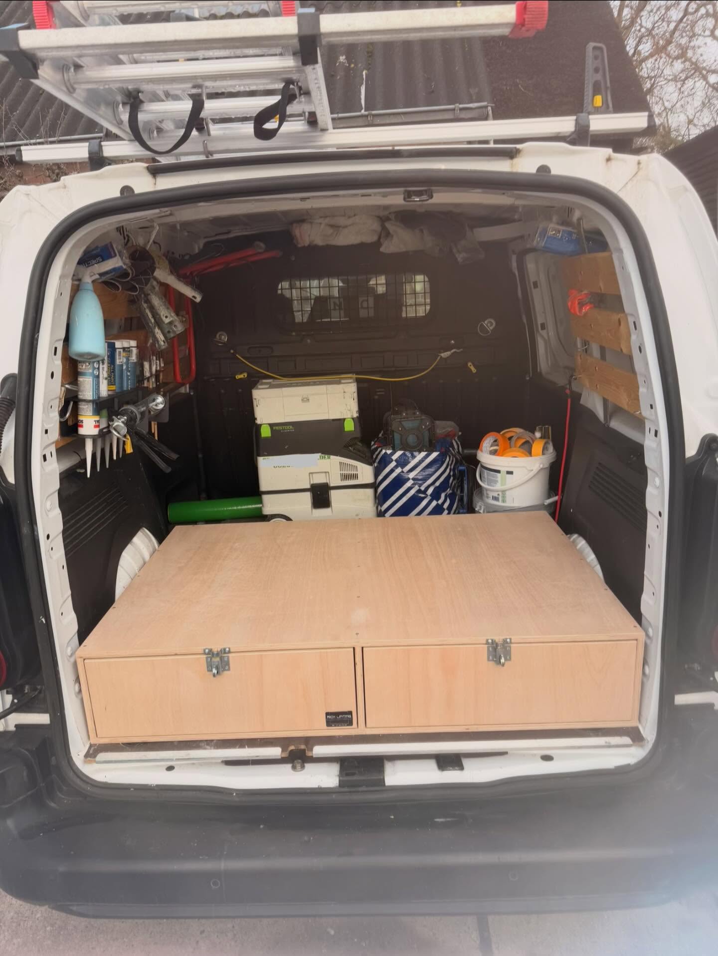 Achterkant van de bus van Rick met een zelfgemaakte houten ladekast en gereedschap